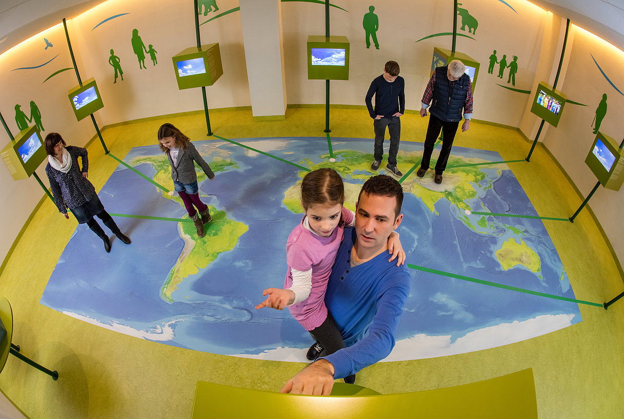 Blick auf Weltkarte im Infozentrum mit Menschen