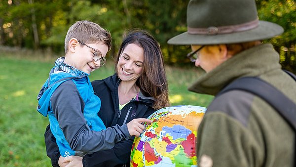 Ranger mit Frau und Kind erklärt Weltkugel