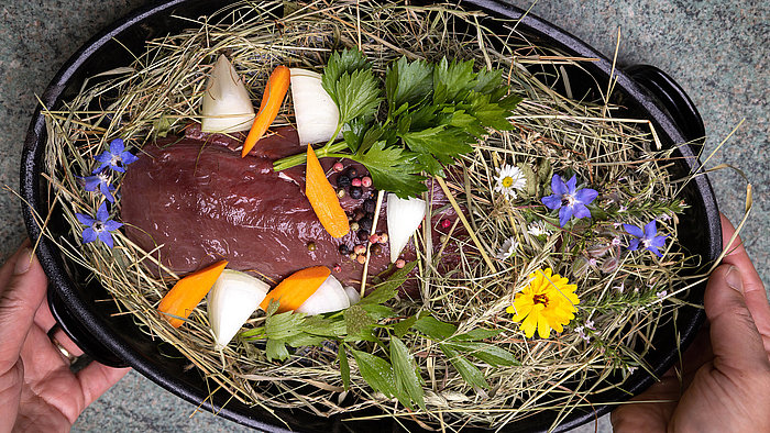 Wildfleisch auf Heubett mit Wildkräutern